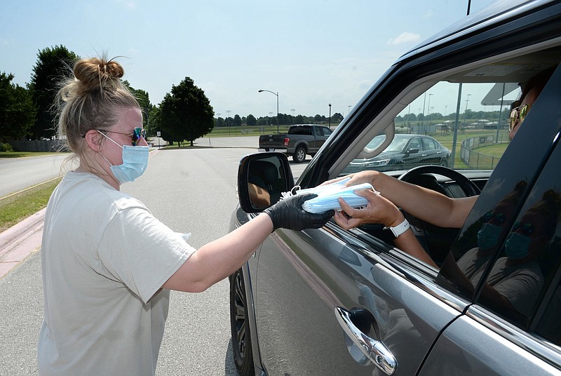 Kayleigh Dockery, a program coordinator with the city of Springdale's Parks and Recreation Department, hands out bundles of face masks at the Randal Tyson Recreation Complex in Springdale in this July 2, 2020, file photo. (NWA Democrat-Gazette/Andy Shupe)