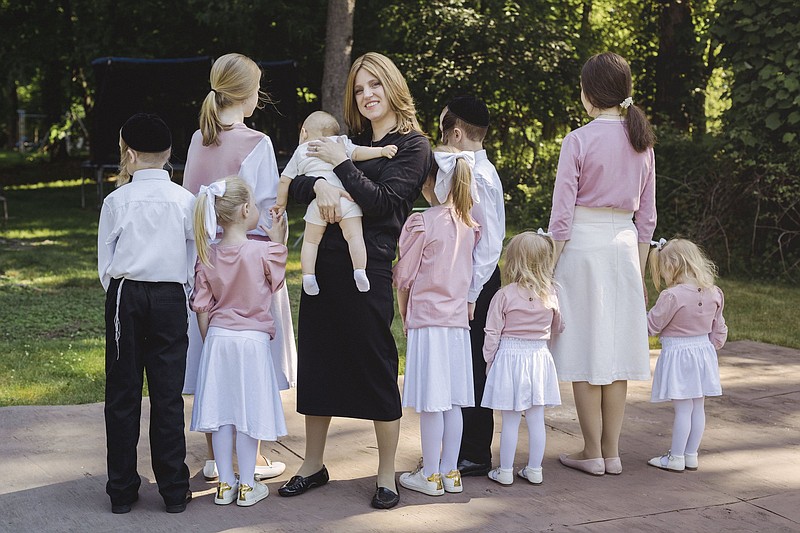 Dr. Alexandra Friedman stands for  a  portrait with  nine  of  her 10 children  in Monsey, N.Y. on June 7. She has navigated strict cultural norms  to become one of the few Hasidic female doctors in the country. She did not want the children’s faces shown for privacy reasons.
(The  New  York  Times/Sara Naomi Lewkowicz)