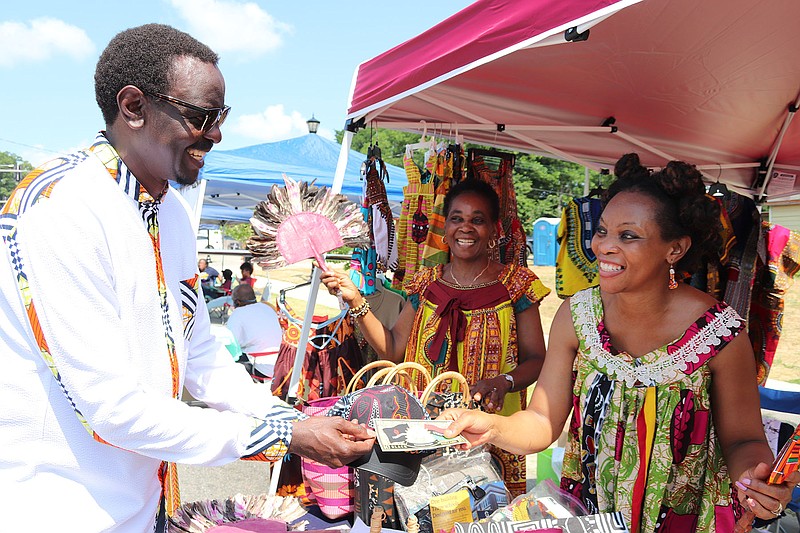 Benito Lubazibwa uses "Black dollars" to make a purchase from Irene Chedjieu of Desirene Afrik while Christine Chedjieu watches at Shop Black @ Wright Avenue, a Juneteenth event promoting black businesses that was held June 19, 2001 on Wright Avenue between Marshall and Battery streets. The event was hosted by ReMix Ideas and Advancing Black Entrepreneurship in partnership with the Wright Avenue Neighborhood Association..(Arkansas Democrat-Gazette -- Helaine R. Williams)
