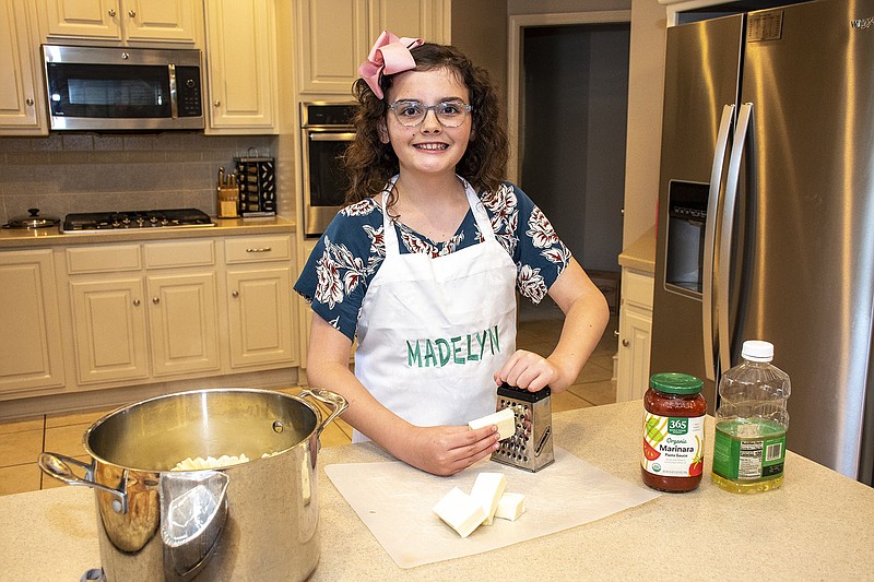 Volunteer Madelyn Lawson grates cheese for a pasta dinner Volunteer Madelyn Lawson grates cheese for a pasta dinner meal on 06/17/2021 . A group of eight kids gathered at the Lawson home to prepare 90 meals to donate to Potluck Food Rescue. The event was part of Kids Cookin‚Äô for a Cause project led by Kids Cook   (Arkansas Democrat-Gazette/Cary Jenkins)