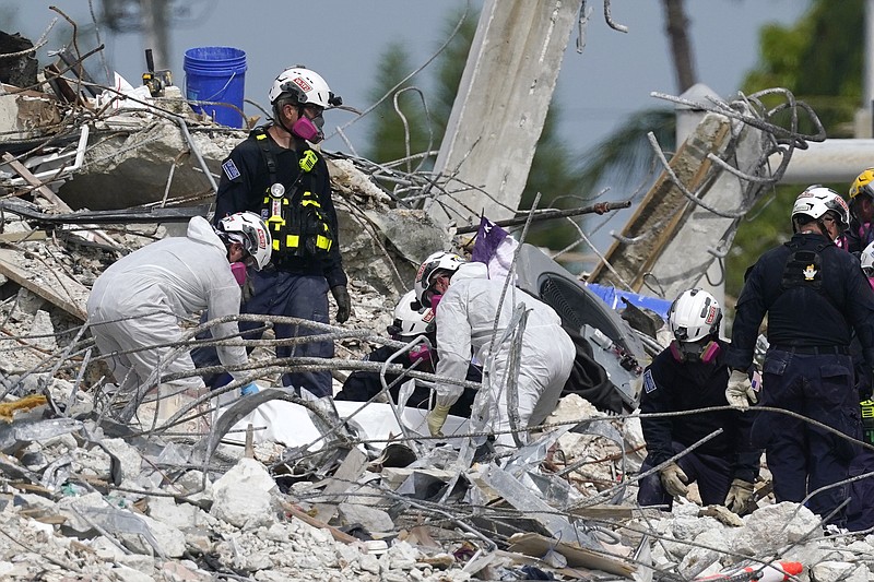 Rescue workers handle a tarp containing recovered remains at the site of the collapsed Champlain Towers South condo building, Monday, July 5, 2021, in Surfside, Fla. (AP/Lynne Sladky)