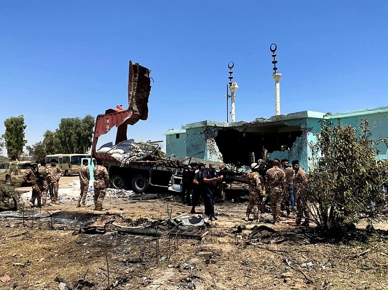 Security forces gather Thursday near a destroyed truck that was used in a rocket attack in Anbar, Iraq.
(AP/Joint Operations Command Media Office)