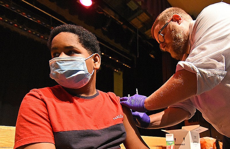 Xavier Hood, 13, receives his first dose of the Pfizer coronavirus vaccine Wednesday, June 9, 2021, from Eric Crumbaugh, a doctor of pharmacy with Express Rx, at Mann Magnet Middle School in Little Rock. (Arkansas Democrat-Gazette/Staci Vandagriff)