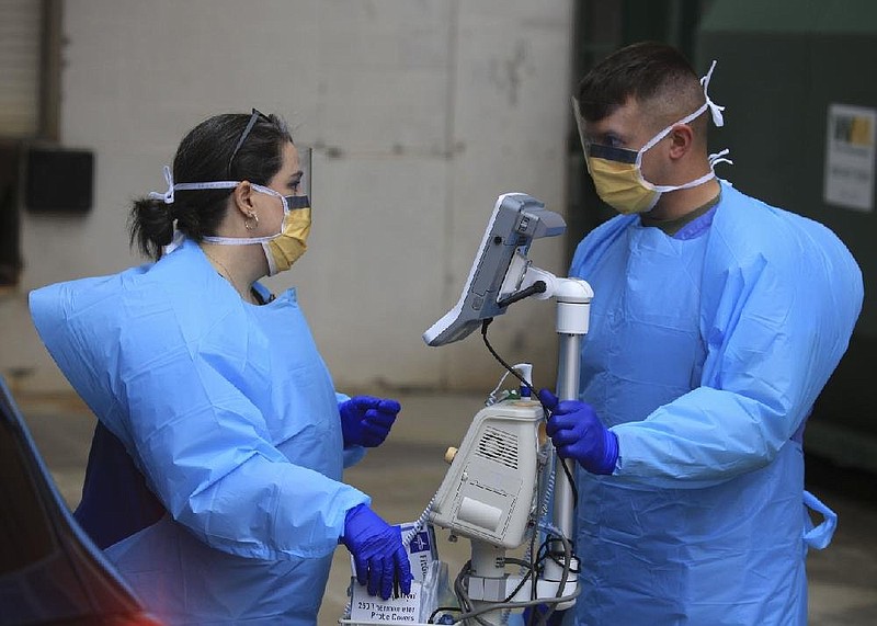 Arkansas Army National Guard Sgt. Jameson Perry (right) works with nurse Katie Anders in Little Rock at the UAMS drive-thru coronavirus testing site in this March 20, 2020, file photo. See more photos from the early days of the pandemic at arkansasonline.com/321virus/. (Arkansas Democrat-Gazette/Staton Breidenthal)