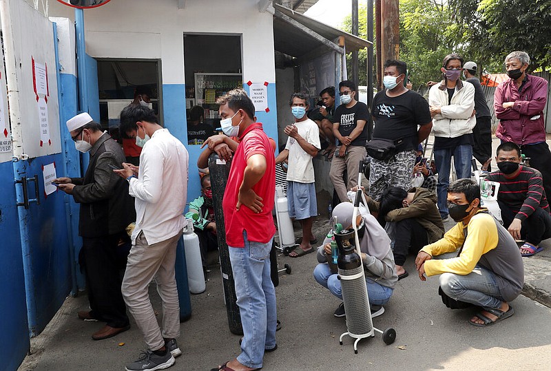 People wait for their turn to refill their oxygen tanks at a recharging station in Jakarta, Indonesia, on Friday, July 9, 2021. Just two months ago, Indonesia was helping India by supplying it with thousands tanks of oxygen. Now, the Southeast Asia country is running out of oxygen as it endures a wave of coronavirus cases, and the government is seeking emergency supplies from other countries, including Singapore and China. (AP/Tatan Syuflana)