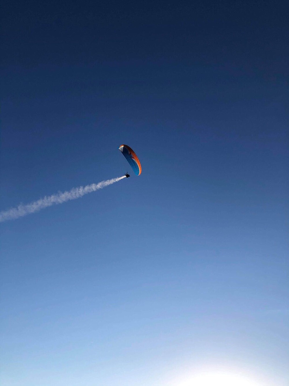 A trail of white smoke can be seen coming from Don Guthrie’s smoke machine attachment on his powered paraglider. (Courtesy of Don Guthrie)