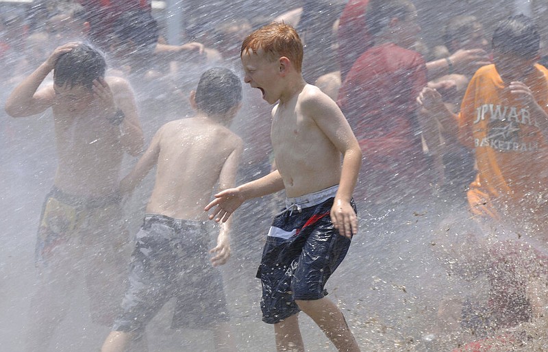 FILE - In this June 9, 2006, file photo, kids from a day camp get soaked by the the fire department at Tyler Junior College in Tyler, Texas. The U.S. has seen a string of COVID-19 outbreaks tied to summer camps in recent weeks in Texas, Illinois, Florida, Missouri and Kansas, offering what some fear could be a preview of the upcoming school year. (Brad Smith/Tyler Morning Telegraph via AP, File)