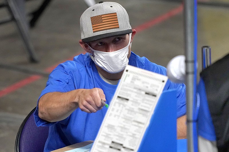 In this May 6 photo, a contractor examines Maricopa County, Ariz., ballots cast in the 2020 general election for Florida-based Cyber Ninjas at Veterans Memorial Coliseum in Phoenix.
(AP/Matt York)