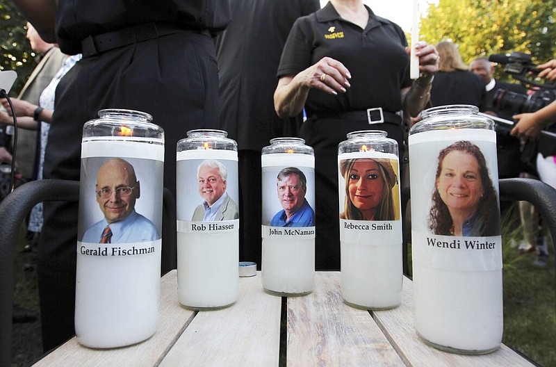 Pictures of five employees of the Capital Gazette newspaper adorn candles during a vigil on June 29, 2018, in Annapolis, Md., across the street from where they were slain in the newsroom. (AP/Jose Luis Magana)