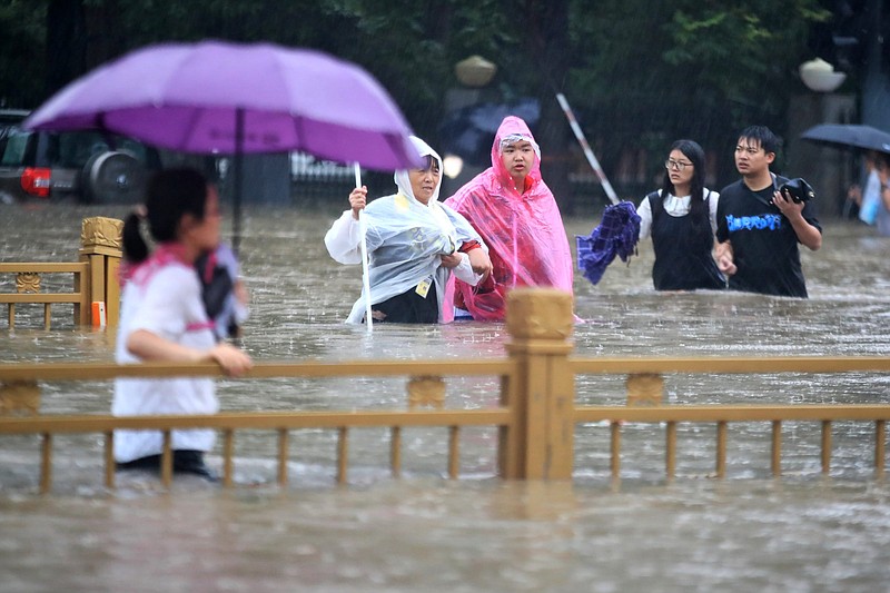 People walk through floodwaters Wednesday in Zhengzhou in central China’s Henan province. Video at arkansasonline.com/722china/.
(AP/Chinatopix)