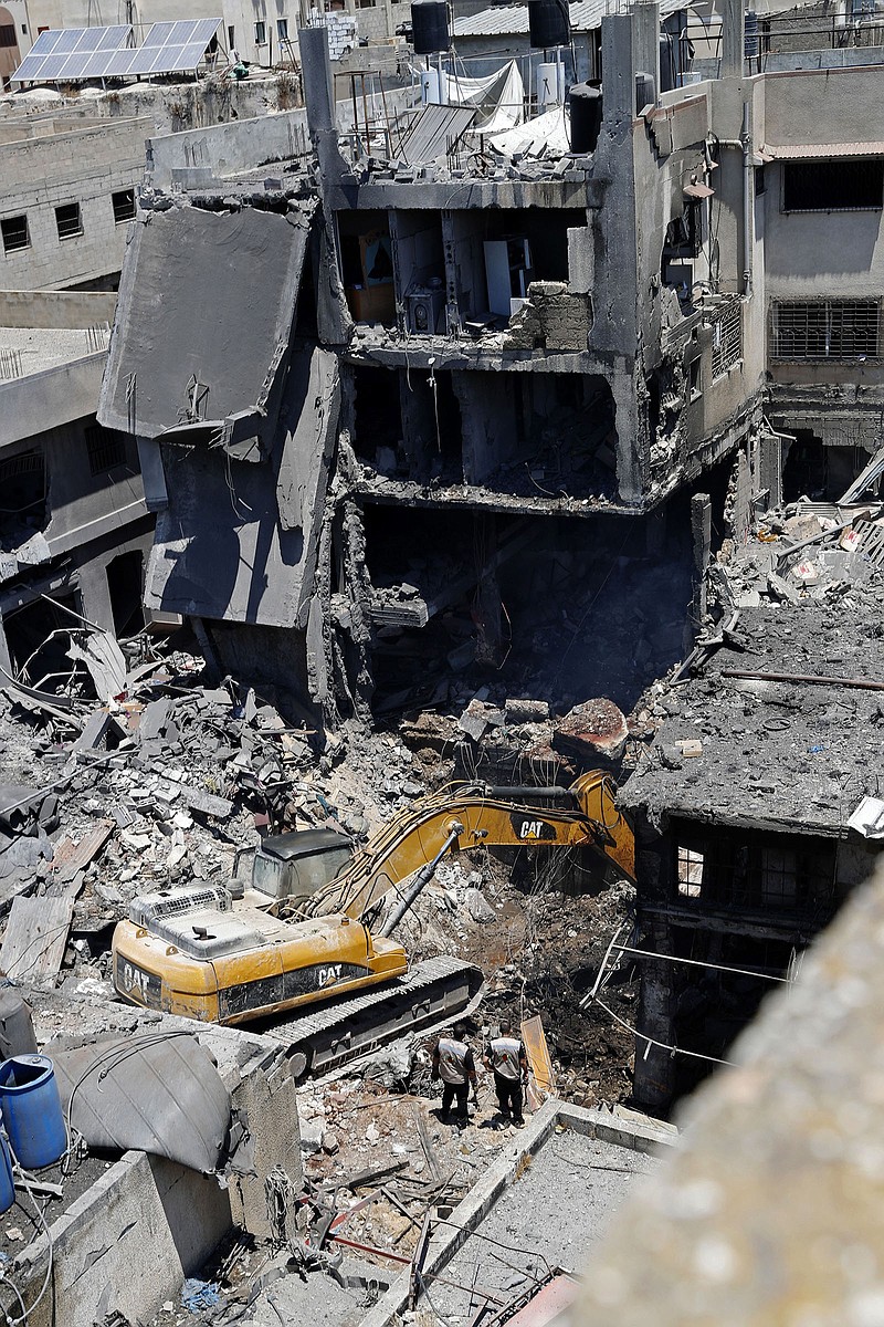 Palestinian security officers watch as a mechanical digger removes rubble Thursday at the site of an explosion in the Al-Zawiya market in Gaza City. More photos at arkansasonline.com/723gazablast/.
(AP/Adel Hana)