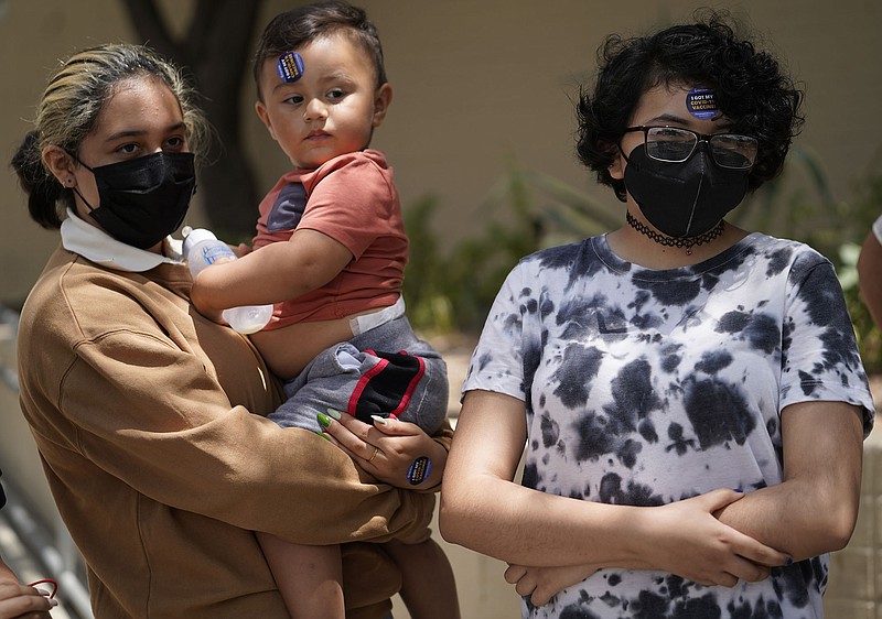 Sarah Villacana, 13, holds 1-year old Christopher Rangel as they and Jaslyn Minchaca, 13, gather with their families Thursday in Los Angeles after getting Pfizer vaccine shots at a county-run site in a city park. More photos at arkansasonline.com/723covid19/.
(AP/Damian Dovarganes)