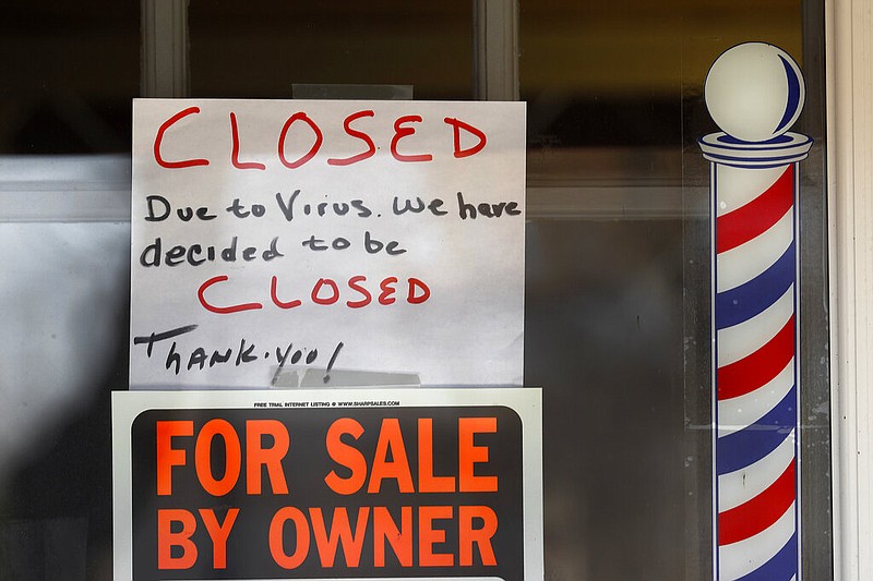 "For Sale By Owner" and "Closed Due to Virus" signs are displayed in the window of a store in Grosse Pointe Woods, Mich., in this April 2, 2020, file photo. (AP/Paul Sancya)