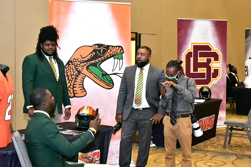 Florida A&M safety Markquese Bell (from left) and offensive lineman Keenan Forbes chat with two other individuals before the start of SWAC Media Day on Tuesday in Birmingham, Ala. Florida A&M’s and Bethune-Cookman’s logos are pictured in the background. 
(Pine Bluff Commercial/I.C. Murrell)