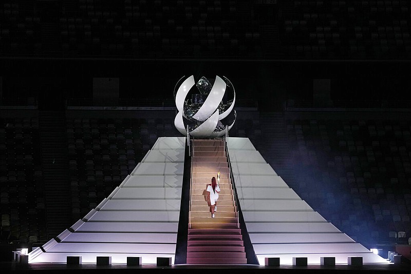 Naomi Osaka climbs stairs to light the Olympic Cauldron during the opening ceremony in the Olympic Stadium at the 2020 Summer Olympics, Friday, July 23, 2021, in Tokyo, Japan. (AP/Kirsty Wigglesworth)