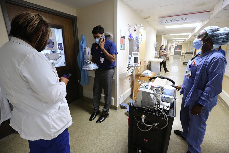 Dr. Ramakrishna Thotakura (center) talks on the phone as nurses Kia Kandlbinder (left) and Brionna Rivers (right) look on while making rounds in one of the Covid wards at University of Arkansas for Medical Science on Thursday, July 22, 2021, in Little Rock. .More photos at www.arkansasonline.com/725covid/.(Arkansas Democrat-Gazette/Thomas Metthe)