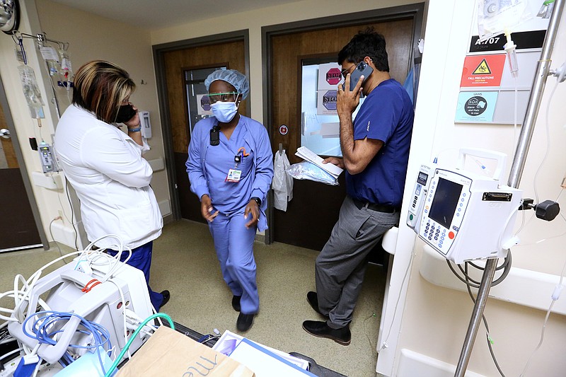 Dr. Ramakrishna Thotakura (right) talks on the phone as nurses Kia Kandlbinder (left) and Brionna Rivers (center) get equipment ready for a patient in one of the Covid wards at University of Arkansas for Medical Science on Thursday, July 22, 2021, in Little Rock. .(Arkansas Democrat-Gazette/Thomas Metthe)