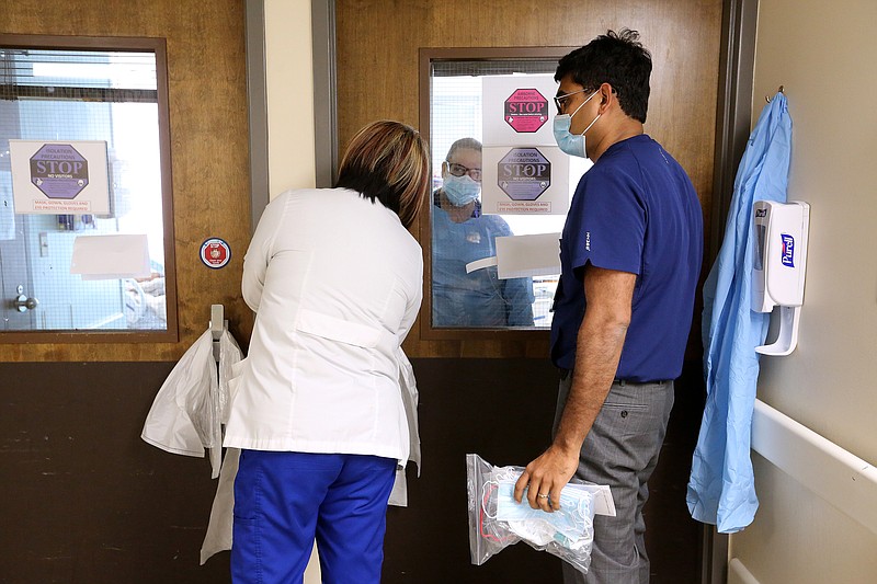 Nurse Kia Kandlbinder (left) and Dr. Ramakrishna Thotakura (right) talk through the door to fellow nurses about treatment of a Covid-19 patient in one of the Covid wards at University of Arkansas for Medical Science on Thursday, July 22, 2021, in Little Rock. .(Arkansas Democrat-Gazette/Thomas Metthe)