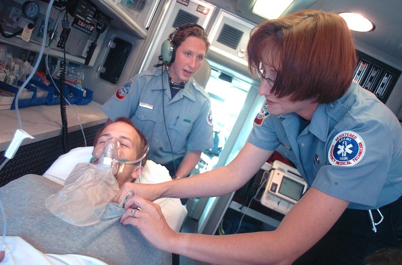 Metropolitan Emergency Medical Services paramedic students Miranda Lattin (left) and Barbara Davis give a demonstration of practicing emergency medical techniques with a volunteer in the back of an MEMS ambulance in this September 2004 file photo. (Arkansas Democrat-Gazette file photo)