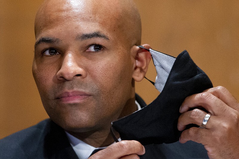 Then-Surgeon General Jerome Adams takes off his mask as he appears on Capitol Hill in Washington in this Sept. 9, 2020, file photo. (Michael Reynolds/Pool via AP)