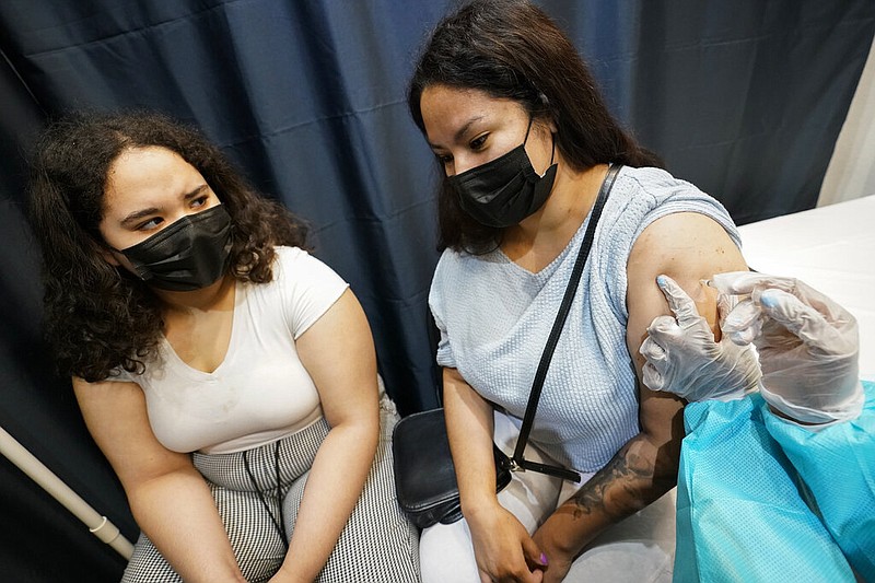 A health care worker inoculates Evelyn Pereira, right, of Brooklyn, with the first dose of the Pfizer covid-19 vaccine as her daughter Soile Reyes, 12, looks on, Thursday, July 22, 2021, at the American Museum of Natural History in New York. (AP/Mary Altaffer)