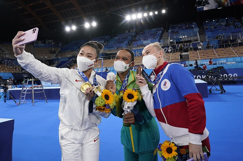 American gold medalist Sunisa Lee (from left), silver medalist Rebeca Andrade of Brazil and bronze medalist Angelina Melnikova of the Russian Olympic Committee take a selfie Thursday after the medal ceremony for the women’s gymnastics all-around competition in Tokyo.
(AP/Gregory Bull)