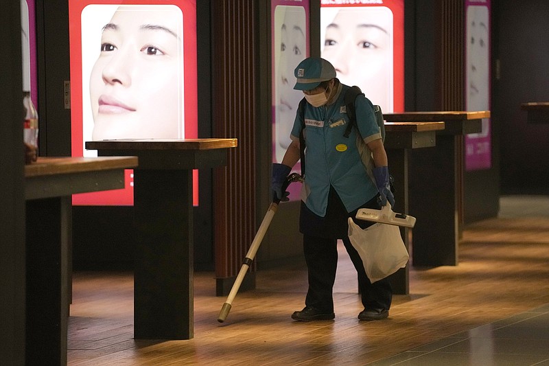 A worker cleans the floor Thursday underneath a subway station in Tokyo. The city had been under a state of emergency even before the start of the Olympics.
(AP/Eugene Hoshiko)