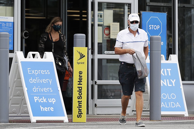In this July 30, 2020 file photo, shoppers wear face masks as they leave a Walmart store in Vernon Hills, Ill. Walmart is reversing its mask policy, Friday, July 30, 2021, and will require vaccinated workers in its distribution centers and stores in areas to wear masks in areas with high infection rates of the virus. (The Associated Press)