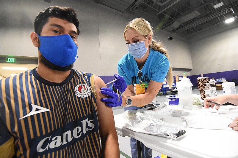 Nery Flores of Little Rock receives his first dose of the Pfizer coronavirus vaccine from Candace Priddy, a physician assistant for UAMS, Saturday, July 31, 2021, during a community wide, back-to-school event at Southwest High School in Little Rock. (Arkansas Democrat-Gazette/Staci Vandagriff)