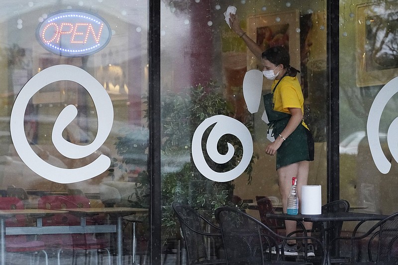 An employee cleans the windows at an ice cream and yogurt store in Buffalo Grove, Ill., in June. Most Americans work in service  industries like food services, one of the categories hit hardest during the pandemic.
(AP)