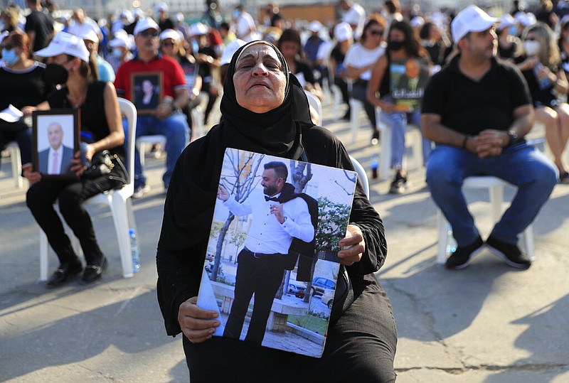 The mother of a victim who was killed in the massive blast last year at the Beirut port holds a portrait of her son as she attends a Mass held to commemorate the first year anniversary of the deadly blast, at the Beirut port, Lebanon, Wednesday, Aug. 4, 2021. (AP/Hussein Malla)
