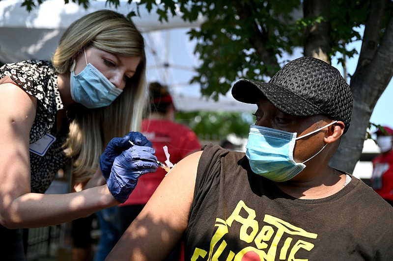 Kayla Marsh, left, gives a dose of the Johnson & Johnson vaccine to Raul J. Johnson during a drive through vaccine clinic in downtown Little Rock on Saturday, Aug. 7, 2021. (Arkansas Democrat-Gazette/Stephen Swofford)