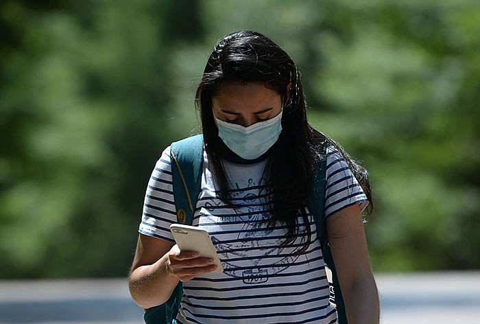 A student passes Old Main on the University of Arkansas, Fayetteville campus on Wednesday, Aug. 11, 2021. As the start of fall classes approaches, all schools in the UA System are implementing face-covering policies for indoor public settings. (NWA Democrat-Gazette/Andy Shupe)
