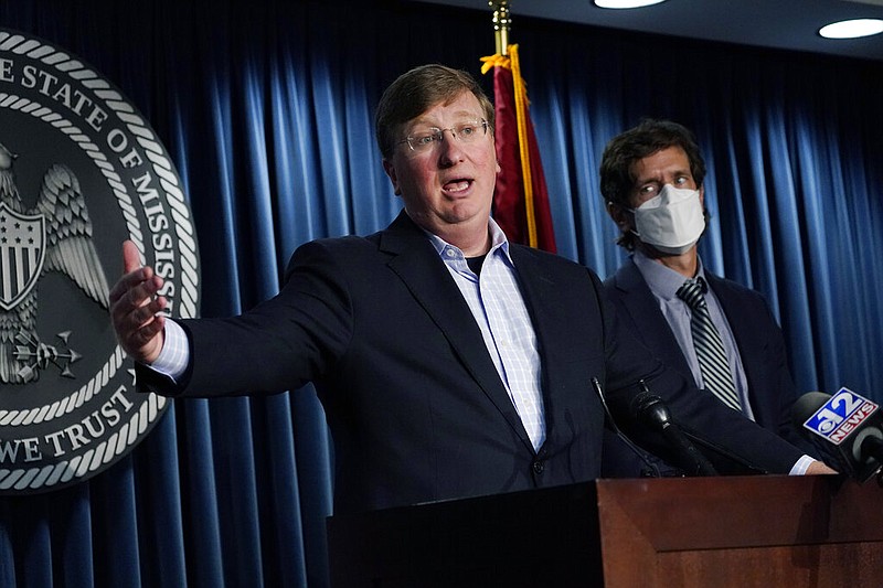 Mississippi State Health Officer Dr. Thomas Dobbs (right) watches as Gov. Tate Reeves respond to a reporter's question in Jackson on Friday, Aug. 13, 2021, during a news briefing regarding Mississippi's covid-19 response. Reeves did not wear a face mask during the 90-minute briefing, during which the governor said that he doesn't believe in "mask shaming" on either side: "I don't believe that you ought to shame someone because they are wearing a mask because you don't believe in them, and I don't believe you ought to shame someone because they're not wearing a mask because you do believe in them." (AP/Rogelio V. Solis)