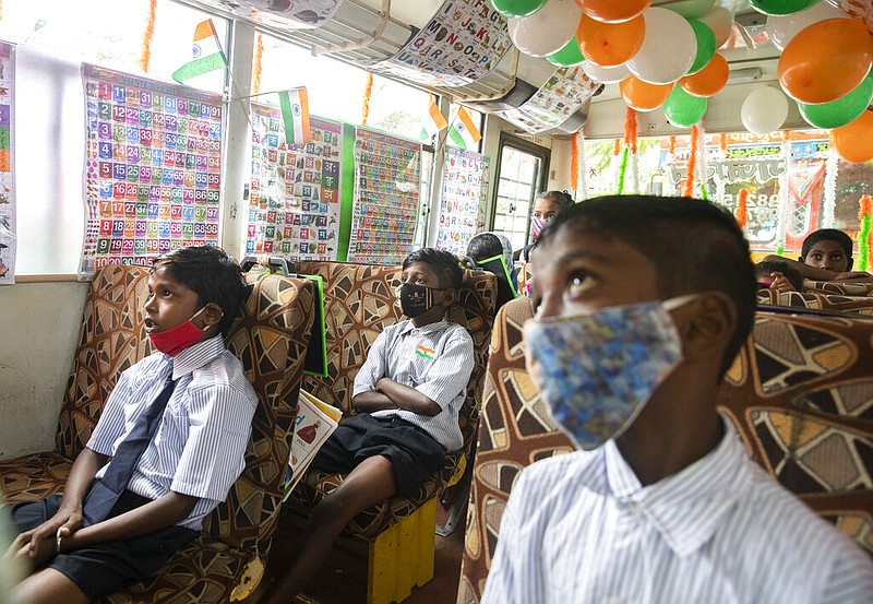 Children wearing masks attend a mobile classroom for children of a slum set up inside a parked bus by a social activist in Mumbai, India, on Sunday, Aug. 15, 2021. (AP/Rafiq Maqbool)