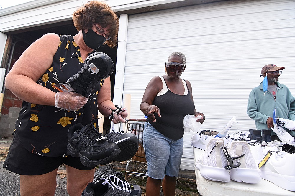 Volunteers Terri Ayers (left) and Tammy Thomas help Oliver Stewart find new shoes Wednesday during the 10th anniversary of Dinner and a Movie by Canvas Community in Little Rock. More photos at arkansasonline.com/819canvas/. (Arkansas Democrat-Gazette/Staci Vandagriff)