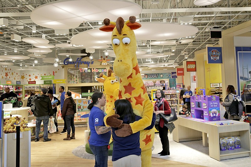 A girl hugs the Toys “R” Us mascot, Geoffrey, at a store in Paramus, N.J., in this file photo. Toys “R” Us is to open shops in more than 400 Macy’s department stores next year.
(AP)
