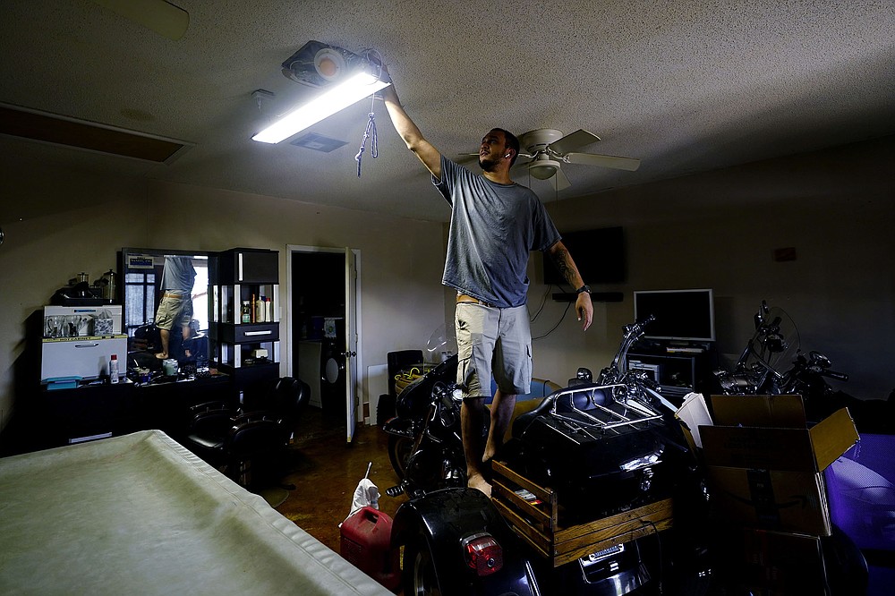 Donnie Pearson adjusts a light at his home Wednesday after power was restored to his neighborhood in New Orleans. Most of New Orleans remains without power, along with much of south Louisiana.
(AP/Eric Gay)