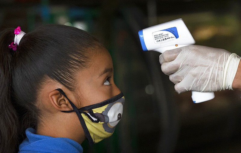 A health worker, checking for symptoms of the novel coronavirus that causes covid-19, takes the temperature of a child wearing a mask in this June 18, 2020, file photo. (AP/Marco Ugarte)
