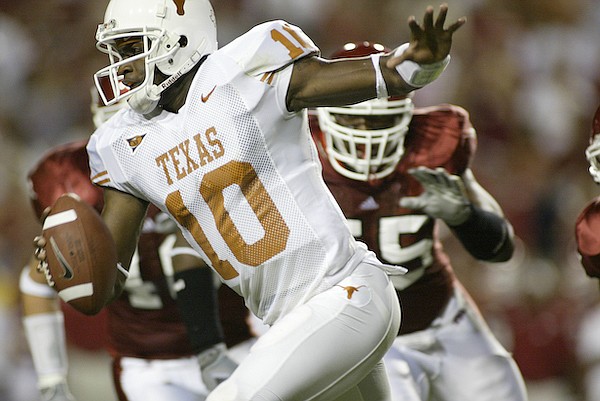 Texas quarterback Vince Young (10) runs from Arkansas defenders during a game Saturday, Sept. 11, 2004, in Fayetteville.