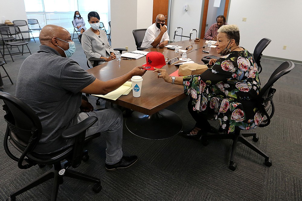 Metropolitan Housing Alliance board member Leta Anthony (right) gives a Little Rock hat to outgoing interim executive director Andy Delaney during the MHA board meeting on Thursday in Little Rock.
(Arkansas Democrat-Gazette/Thomas Metthe)