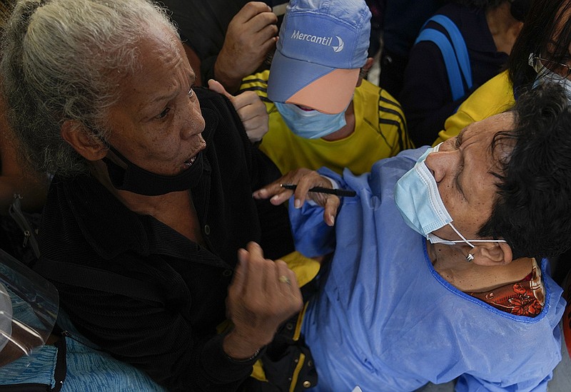 A health worker takes the names of people gathered outside a vaccination center Thursday in Caracas, Venezuela, to get a second dose of the Sputnik V covid-19 vaccine. The Venezuelan government is beginning rollouts of second doses after months of delays.
(AP/Ariana Cubillos)