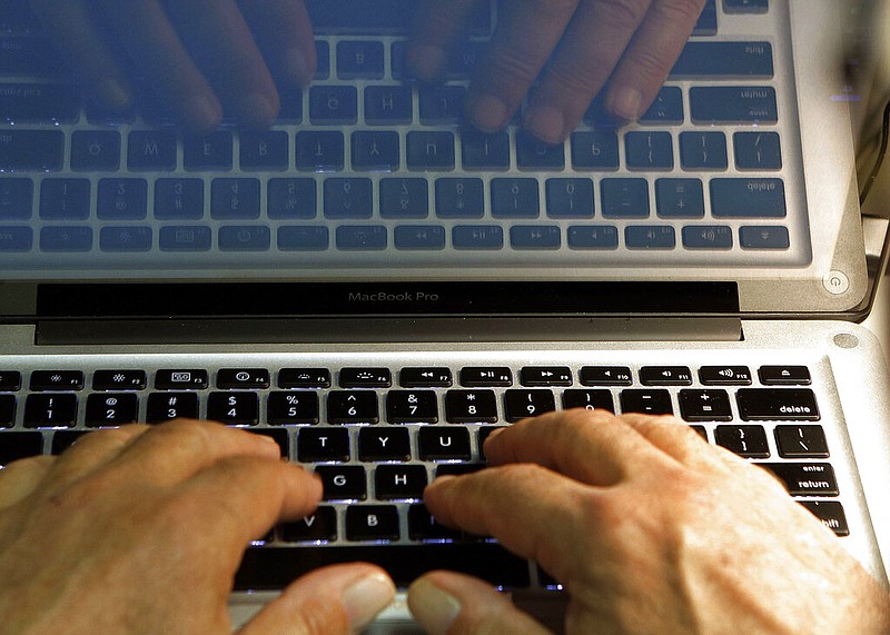 Hands type on a laptop computer keyboard in this Feb. 27, 2013, file photo. (AP/Damian Dovarganes)