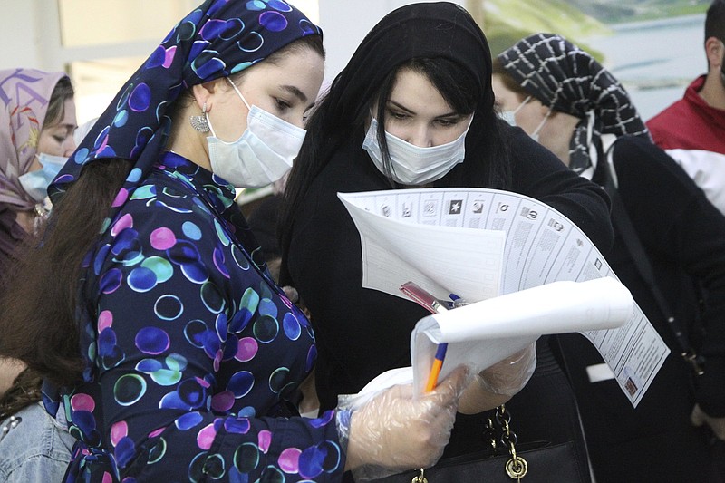 Chechen women read their ballots at a polling station Saturday during parliamentary elections in Grozny, Russia. Video online at arkansasonline.com/919ruvote/.
(AP/Musa Sadulayev)