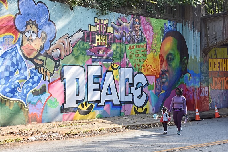 Loni Rainey of Little Rock walks with her daughter Octavia, 3, along the part of Little Rock's Seventh Street lined with murals honoring Peace Week in this Sept. 20, 2020, file photo. (Arkansas Democrat-Gazette/Staci Vandagriff)