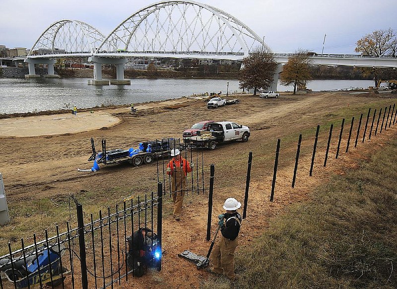 Alan Gordon (from left), Stony Hayes and Joe Green with Jacor Construction install a fence in North Little Rock's Riverfront Park in this Dec. 6, 2017, file photo. (Arkansas Democrat-Gazette/Staton Breidenthal)