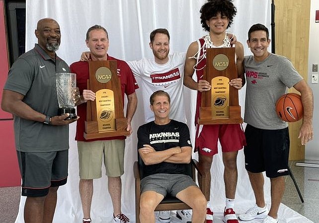 Arkansas coach Eric Musselman and his staff show off some of the program's trophies, including the 1994 national championship trophy, with Anthony Black.