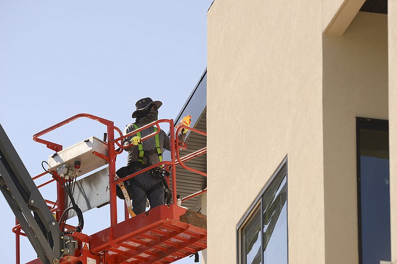 FILE -- Javo Ruiz, a construction worker from Grindstone Construction, hands off a drink as he installs soffit and fascia, Monday, August 30, 2021 at the Promenade Commons in Bentonville. 
(NWA Democrat-Gazette/Charlie Kaijo)