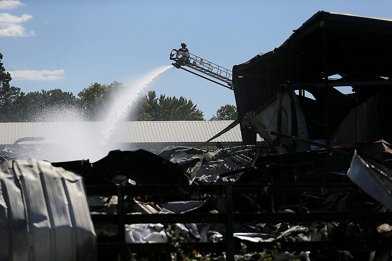 A Little Rock firefighter sprays water on hot spots Wednesday on the charred remains of the Goldman Logistics recycling warehouse in Little Rock. More photos at arkansasonline.com/923aftermath/.
(Arkansas Democrat-Gazette/Thomas Metthe)