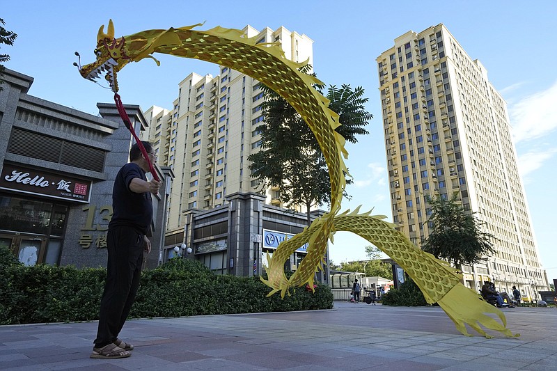 A man displays a cloth dragon Tuesday outside the Evergrande Yujing Bay residential complex in Beijing. Global investors are watching nervously as Evergrande, one of China’s biggest real estate developers, works to avoid default on tens of billions of dollars of debt.
(AP/Ng Han Guan)